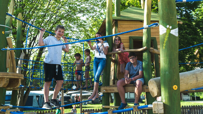 Kinder spielen auf einem Spielplatz mit vielen Hängebrücken und Klettermöglichkeiten