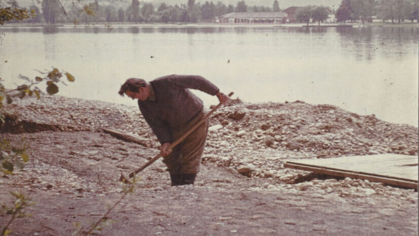 altes Foto von einem mit der Schaufel arbeitenden Mann am See