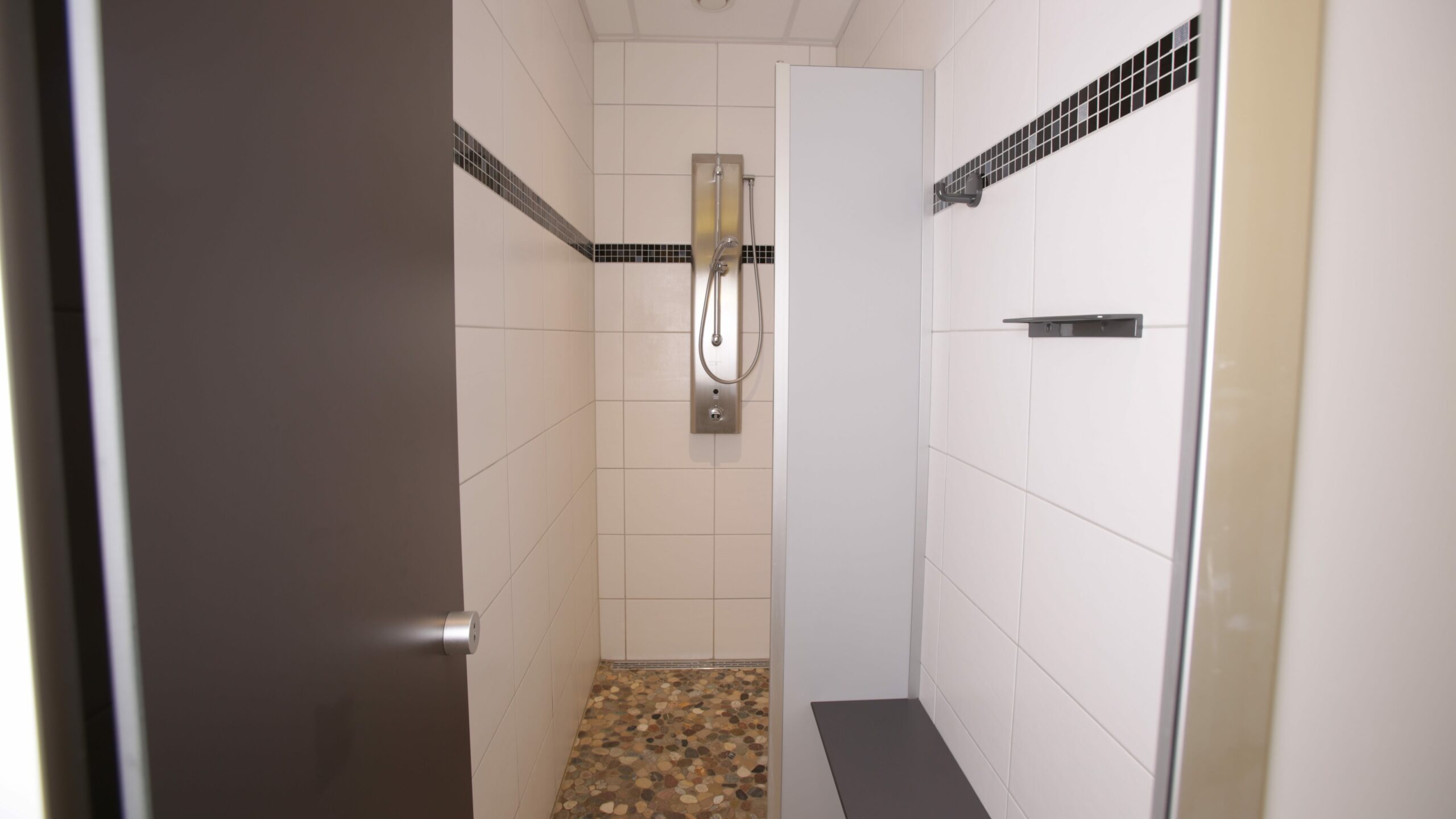 Eine saubere, modern geflieste Dusche in den Sanitäranlagen