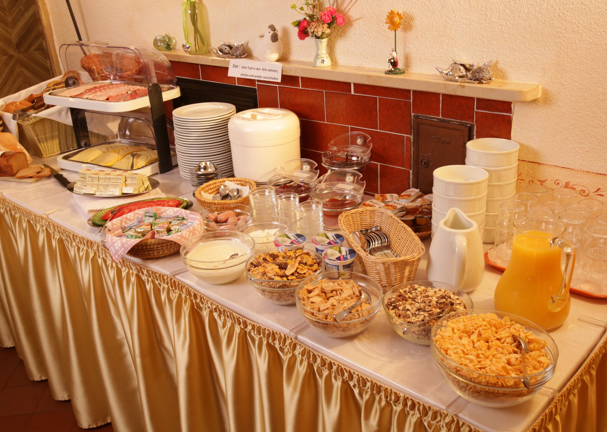 Ein voll gedeckter Buffet-Tisch mit frischem Orangensaft, einer Müsliauswahl, Joghurt, Aufstrichen und Belag und frischen Semmeln